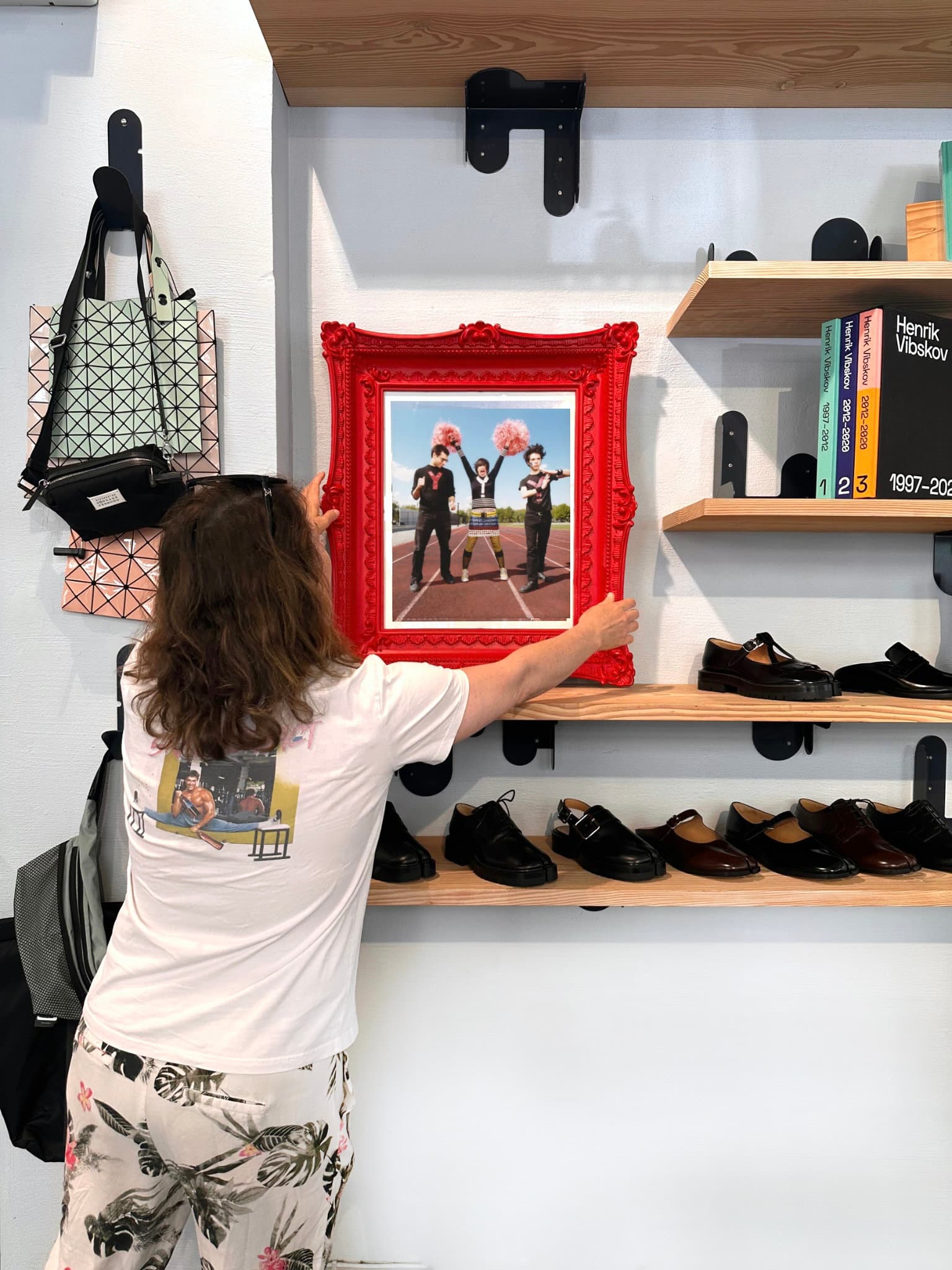 Emily Wilson hanging a red ornate framed print in a shop